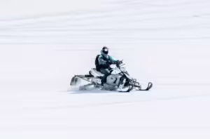 male riding snowmobile large snowy field