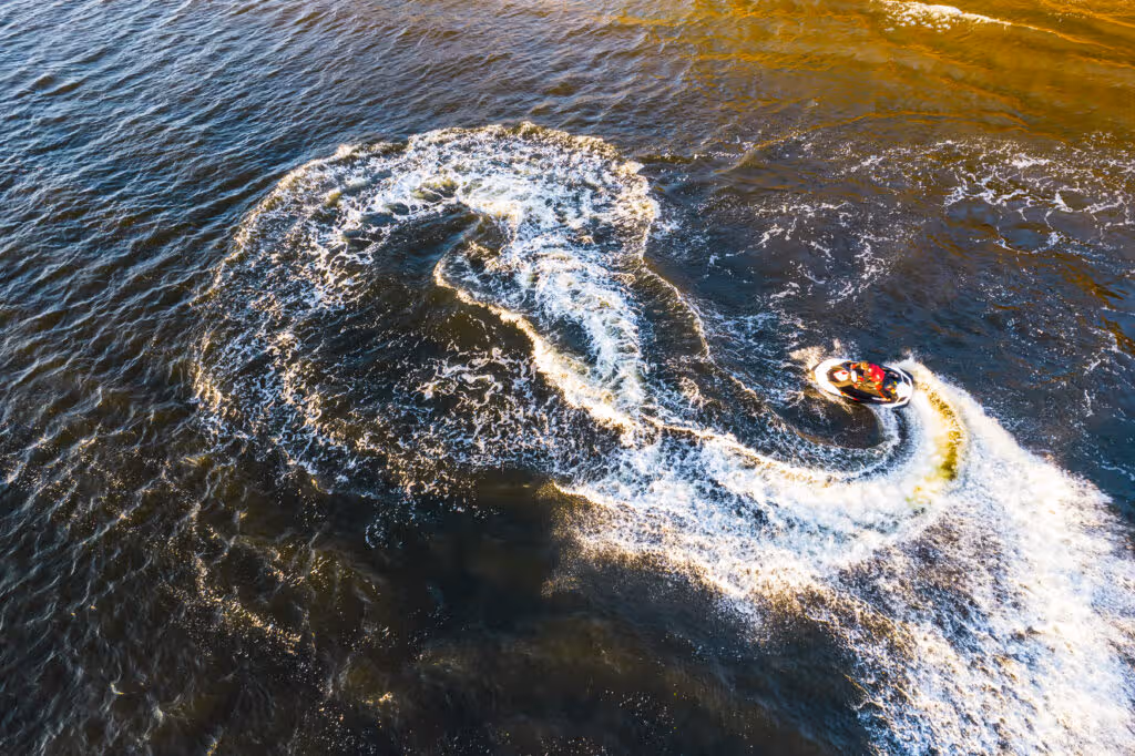 aerial view young man making infinite loop riding fast water scooter sunset golden water