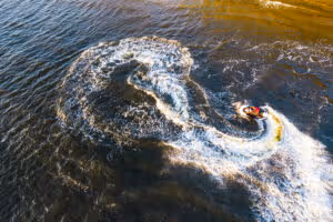 aerial view young man making infinite loop riding fast water scooter sunset golden water
